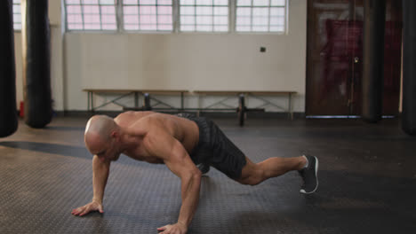 Caucasian-muscular-shirtless-bald-man-exercising,-doing-push-ups
