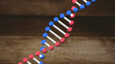 Animation-of-dna-strand-spinning-over-wooden-background