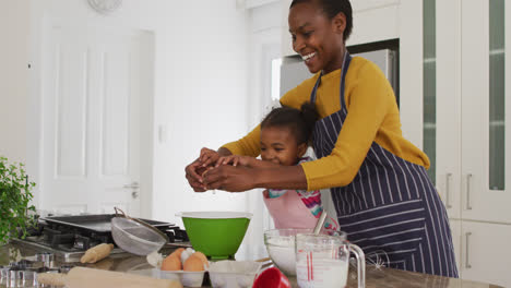 Feliz-Madre-E-Hija-Afroamericana-Usando-Delantales-Divirtiéndose-Mientras-Cocinan-En-La-Cocina