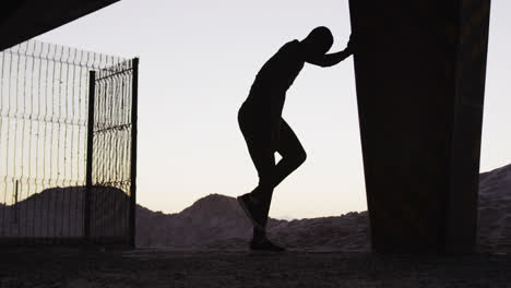 Silhouette-of-focused-african-american-man-exercising-outdoors,-stretching