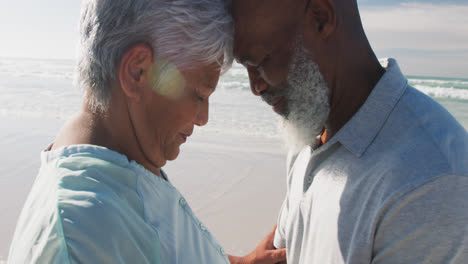 Senior-african-american-couple-touching-each-other-foreheads-at-the-beach