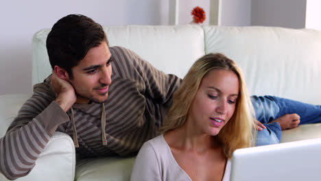 Happy-young-couple-sitting-on-the-couch-using-the-laptop