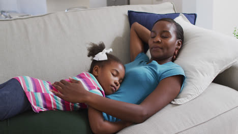 Happy-african-american-mother-and-daughter-lying-on-sofa-and-relaxing-with-eyes-closed