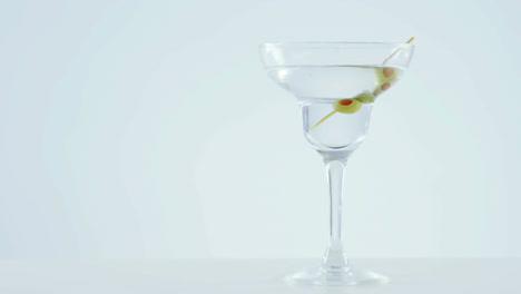 Chevron-Muster-Design-über-Oliven-Im-Cocktailglas-Vor-Grauem-Hintergrund