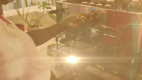 Animation-of-lens-flare-and-sunlight-with-hands-of-barista-preparing-coffee-using-machine