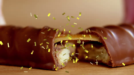 Animation-of-gold-confetti-falling-over-broken-biscuit-and-caramel-chocolate-bar