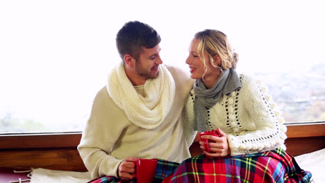 Cute-couple-relaxing-together-under-a-blanket-in-their-winter-cabin
