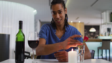Mixed-race-man-having-romantic-dinner-at-restaurant-holding-wine-glass-and-talking-to-camera