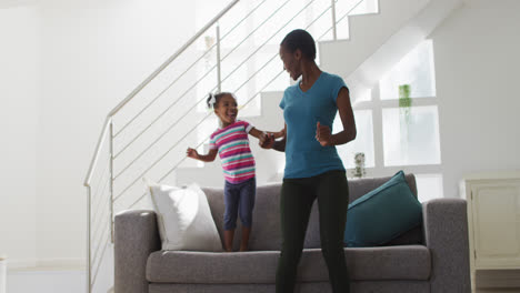 Happy-african-american-mother-and-daughter-dancing-and-having-fun-at-home