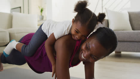 Happy-african-american-mother-and-daughter-doing-exercise-at-home