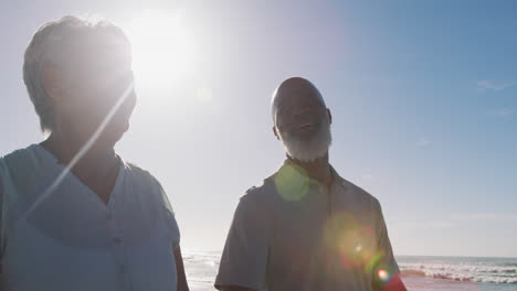 Lächelndes-älteres-Afroamerikanisches-Paar,-Das-Am-Strand-Spazieren-Geht-Und-Händchen-Hält