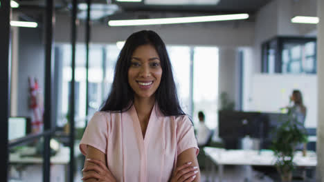 Portrait-of-mixed-race-businesswoman-standing-in-office-with-arms-crossed-smiling-to-camera
