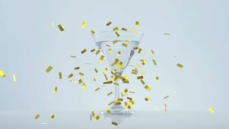 Golden-confetti-falling-over-olives-falling-into-cocktail-glass-against-grey-background