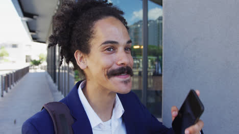 Mixed-race-man-with-moustache-walking-on-the-street-and-talking-on-smartphone