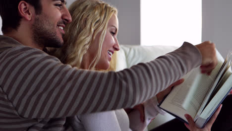Happy-young-couple-reading-together-on-the-couch-