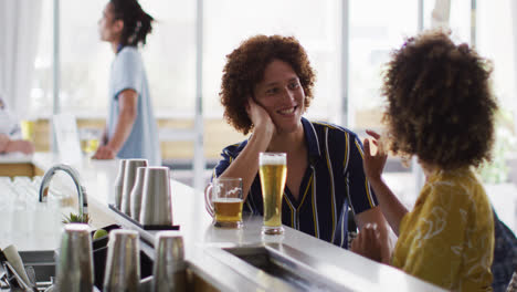 Diverse-group-of-happy-friends-drinking-beers-and-talking-at-a-bar