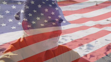 Animation-of-american-flag-waving-over-senior-man-on-beach