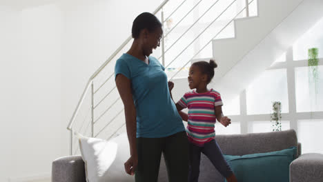 Happy-african-american-mother-and-daughter-dancing-and-having-fun-at-home