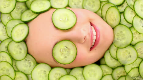 Smiling-womans-face-surrounded-by-cucumber-slices-