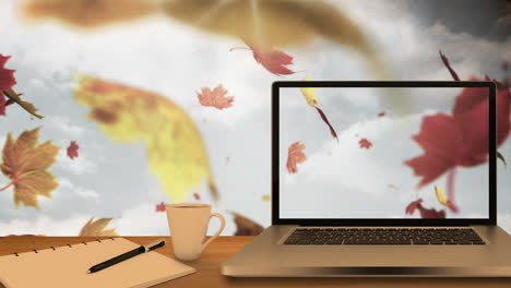 Desktop-computer-and-office-equipment-on-a-table-against-autumn-maples-leaves-floating-in-blue-sky