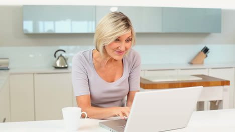 Blonde-woman-drinking-coffee-using-her-laptop