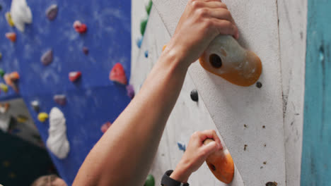 Close-up-of-caucasian-woman-climbing-up-a-wall-at-indoor-climbing-wall