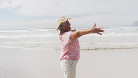 Mixed-race-senior-woman-spinning-with-open-hands-at-the-beach