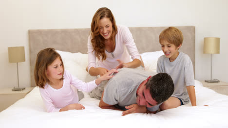 Süße-Eltern-Und-Kinder-Liegen-Auf-Dem-Bett-Und-Spielen-Herum