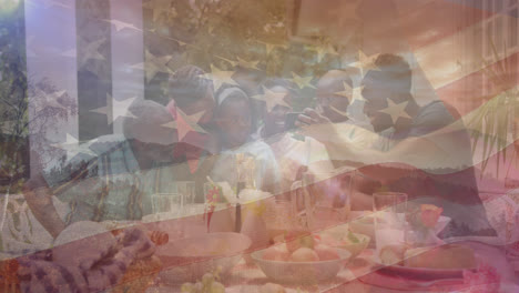 Animation-of-flag-of-united-states-of-america-over-african-american-family-eating-dinner-in-garden
