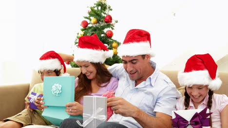 Familie-öffnet-Ihre-Weihnachtsgeschenke-Auf-Der-Couch