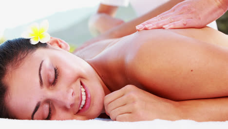 Smiling-brunette-enjoying-a-massage-poolside