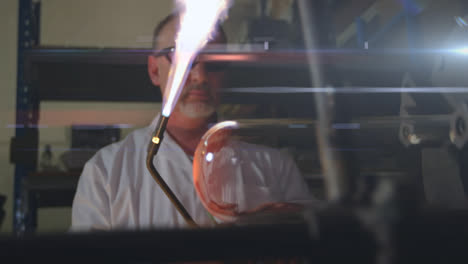 Animation-of-glowing-light-over-caucasian-man-using-flame-torch-working-in-factory