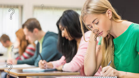 Animation-of-question-marks-over-diverse-teenage-students-writing-in-class