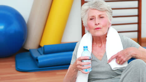 ältere-Frau-Sitzt-Auf-Dem-Boden-Und-Trinkt-Wasser