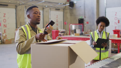 African-american-male-and-female-workers-wearing-safety-suits-and-packing-boxes-in-warehouse
