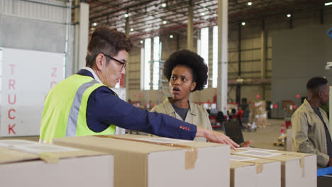 Diverse-male-and-female-workers-with-boxes-talking-in-warehouse