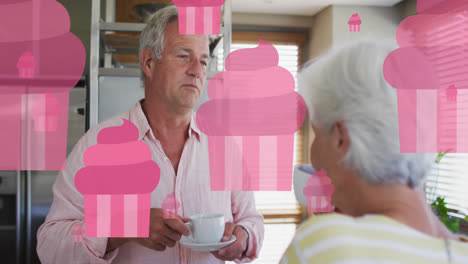 Animation-of-pink-fairy-cakes-over-happy-caucasian-senior-couple-talking-and-drinking-tea