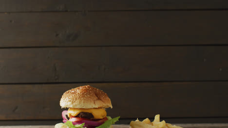 Video-of-cheeseburger-and-chips-against-rustic-wooden-background-with-copy-space