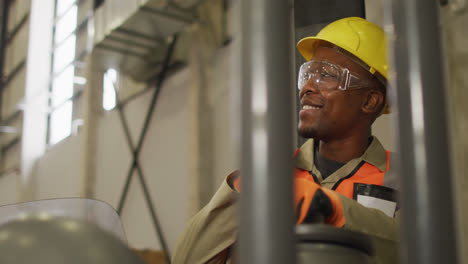 African-american-male-worker-wearing-safety-suit-with-helmet-talking-in-warehouse