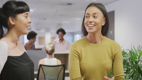 Diverse-female-business-colleagues-talking-and-smiling-in-office