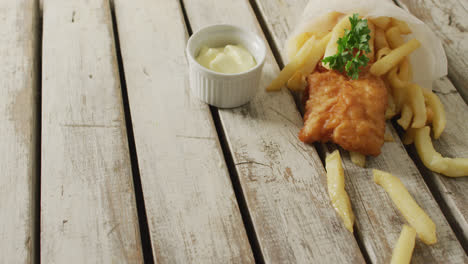 Video-of-wrapped-fish-and-chips-with-dip,-on-rustic-table-top-with-copy-space