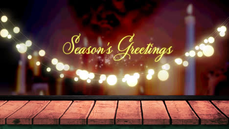 Seasons-greetings-text-and-glowing-yellow-fairy-light-decoration-hanging-over-wooden-plank