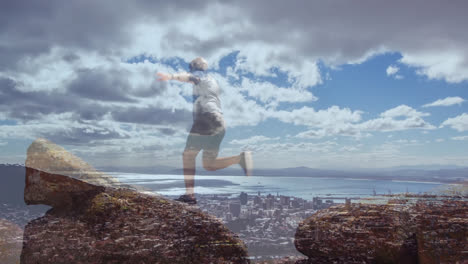 Composite-of-senior-man-running-and-jumping-on-rocks-by-coast,-and-cloudy-blue-sky-over-sea