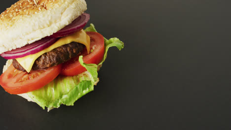 Video-of-cheeseburger-with-salad-in-burger-bun,-on-grey-background-with-copy-space