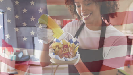 Composite-of-smiling-african-american-woman-preparing-hotdog,-and-waving-american-flag