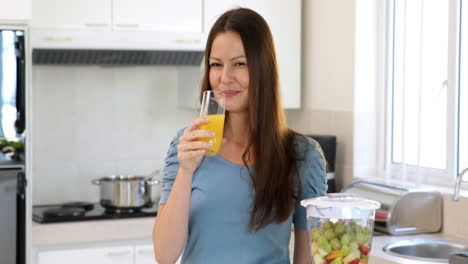 Smiling-woman-drinking-glass-of-orange-juice
