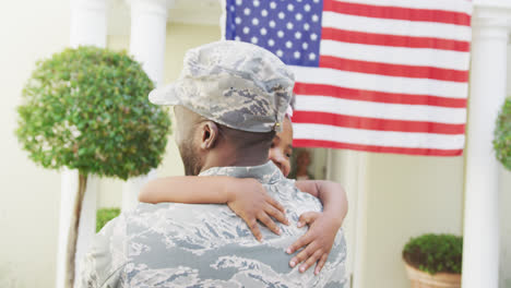 African-american-male-soldier-embracing-his-smiling-daughter-over-american-flag