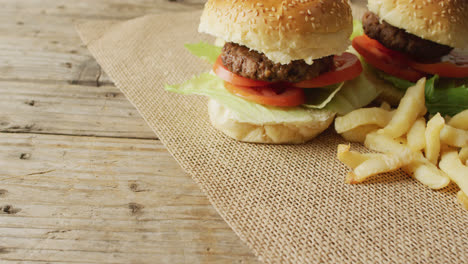 Video-of-two-burgers-and-chips-on-sackcloth-and-wooden-table