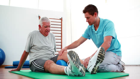 Physiotherapist-helping-patient-with-his-knee-mobility