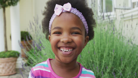 Portrait-of-smiling-african-american-girl-looking-at-camera-in-garden